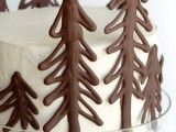 a white wedding cake with chocolate fir trees is a simple and lovely idea for a winter wedding