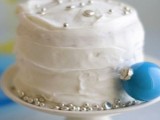 a white textural wedding cake topped with silver edible beads and with a blue ornament on the side is amazing