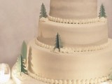 a white wedding cake decoated with small sugar Christmas trees and topped with snowmen is amazing for a fun wedding
