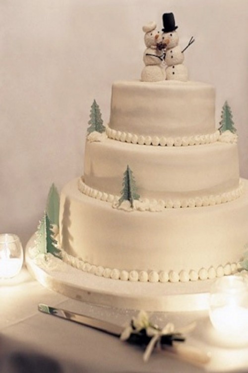 a white wedding cake decoated with small sugar Christmas trees and topped with snowmen is amazing for a fun wedding