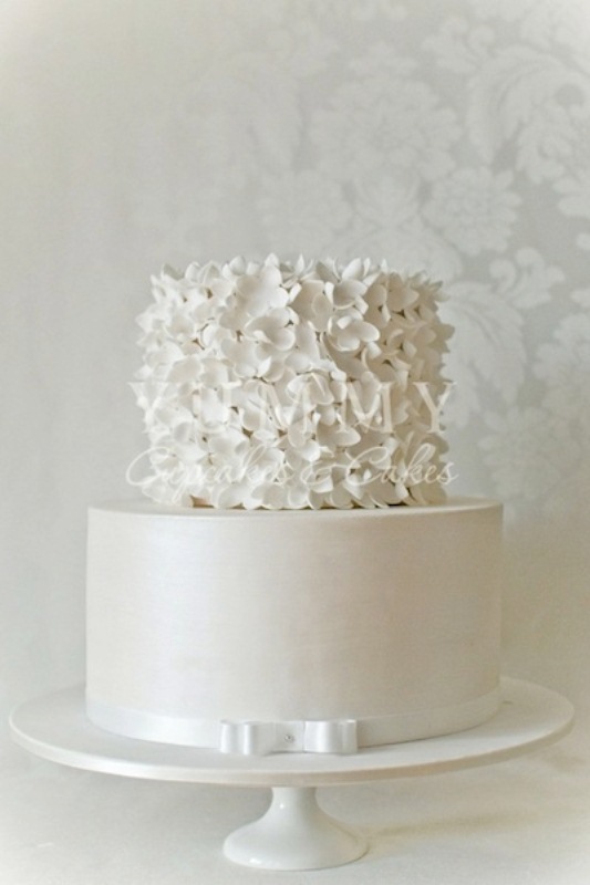 A neutral wedding cake with a sleek lower tier and a white flower one on top is a gorgeous and romantic idea