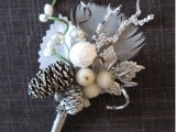 a sparkling winter wedding boutonniere with berries, beads, snowy pinecones, feathers, branches and shiny touches