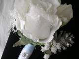 a shiny winter boutonniere with a glowing white rose, sparkling pinecones and some leaves