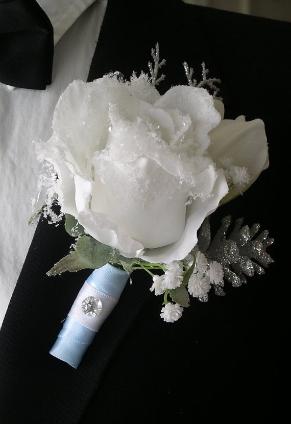 A shiny winter boutonniere with a glowing white rose, sparkling pinecones and some leaves