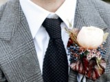 a winter wedding boutonniere with berries, little blooms and a large white peony rose, dark leaves and herbs