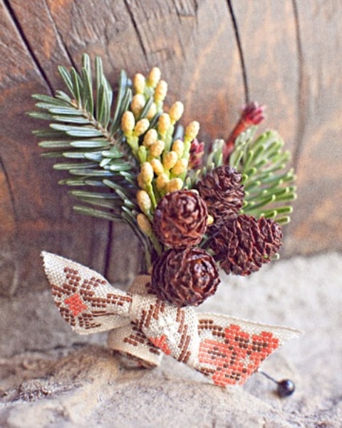 a rustic winter boutonniere with pinecones, berries, fir branches and printed ribbon in a bow for a winter groom