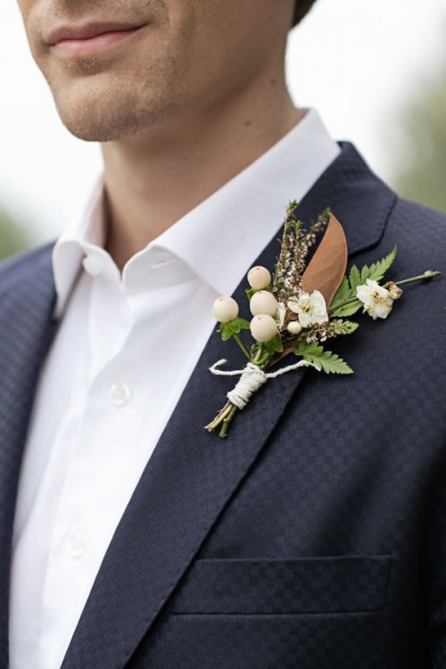 a relaxed winter wedding boutonniere of berries, greenery, white blooms and magnolia leaves looks elegant