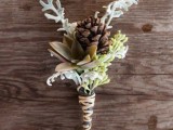 a rustic winter wedding boutonniere of greenery and pale leaves, pinecones and a succulents plus a twine wrap for a winter groom