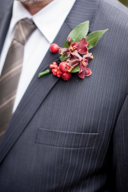 a red winter boutonniere of blooms, berries and leaves is a bold accent for a winter groom's look