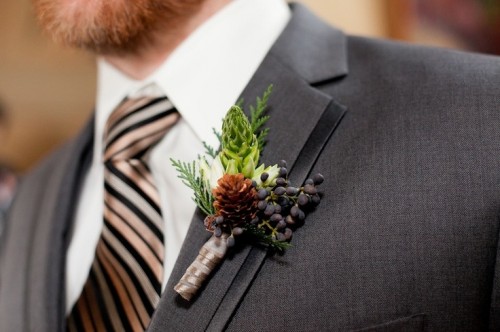 a white bloom, a pinecone, berries and greenery for accessorizing a winter groom's look and make it chic