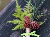 ferns, pinecones and twine plus a green bow make up a chic and cool woodland wedding boutonniere for a winter groom