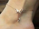 a delicate gold chain anklet with a butterfly and rhinestones hanging down is a stylish addition to a summer bridal look