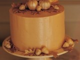 an amber buttercream wedding cake decorated with sugar leaves and mini pumpkins is great for a fall wedding