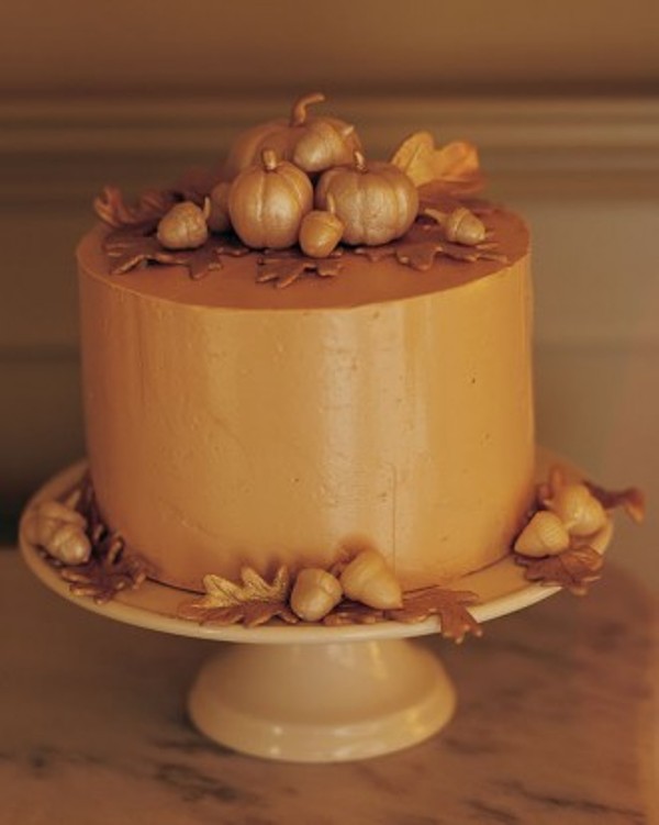 An amber buttercream wedding cake decorated with sugar leaves and mini pumpkins is great for a fall wedding