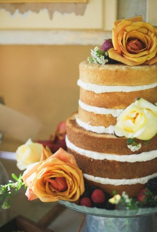 A naked wedding cake decorated with berries and amber and copper roses is great for a fall wedding