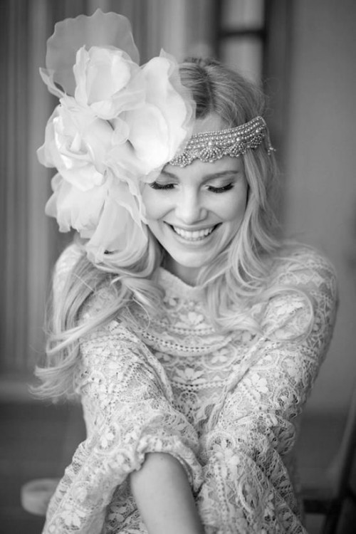 a sparkling rhinestone headpiece with an oversized fabric flower on one side for a glam boho bride