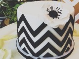 a round black and white chevron wedding cake topped with a black and white flower is a stylish idea for a wedding with black and white color scheme