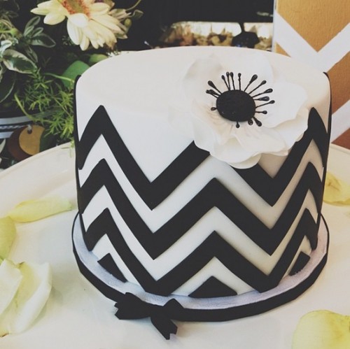 a round black and white chevron wedding cake topped with a black and white flower is a stylish idea for a wedding with black and white color scheme