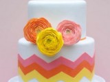 a white wedding cake decorated with pink, coral and yellow chevrons and matching ranunculus is a lovely idea for a wedding with this color scheme