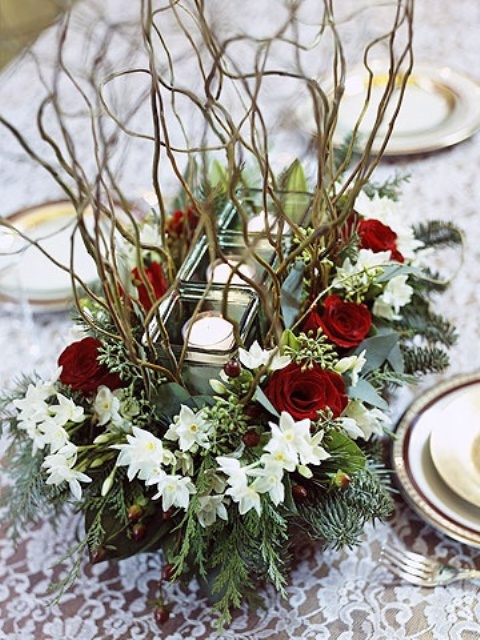 a frozen Christmassy wedding centerpiece of greenery, branches, white and burgundy blooms and candles in the center