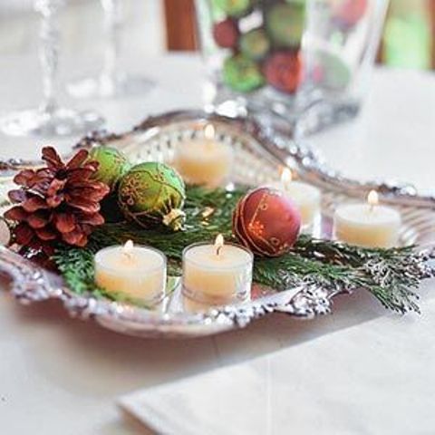 a silver tray with candles, greenery, pinecones and ornaments is a refined and beautiful Christmas wedding centerpiece
