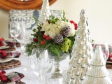 a beautiful Christmas wedding centerpiece of a bowl filled with white, green blooms, greenery, berries and shiny fir trees