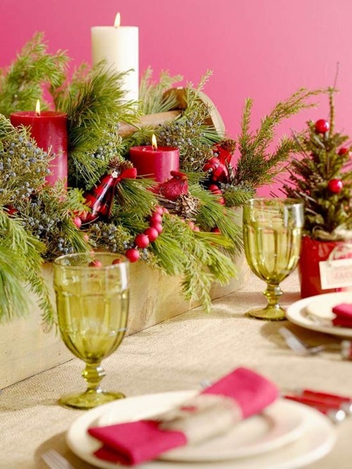 a lush and bold Christmas wedding centerpiece of a wooden box filled with fir branches, red berries, candles and pinecones plus mini trees in bowls