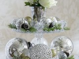 a tiered glass stand with silver and silver glitter ornaments, fir branches and white blooms is very elegant and very chic