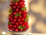 a pretty edible Christmas wedding centerpiece of a Christmas tree made of strawberries and mint and placed into a porcelain bowl