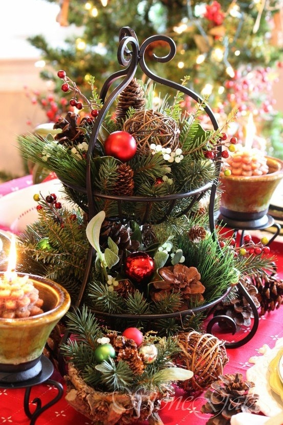 A tiered metal stand with fir branches, pinecones, vine balls, berries and red Christmas ornaments is great for a rustic wedding