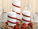 a metallic plate with gold and red ornaments and white candles with red ribbons is easy to make