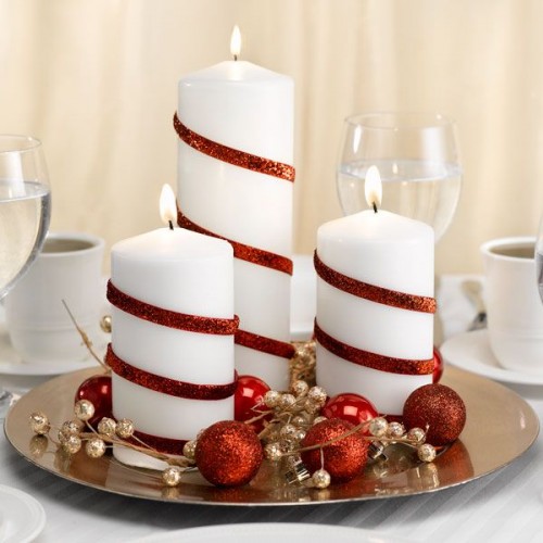 a metallic plate with gold and red ornaments and white candles with red ribbons is easy to make