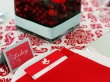 a square glass bowl with cranberries and red blooms is a lovely and easy Christmas wedding centerpiece