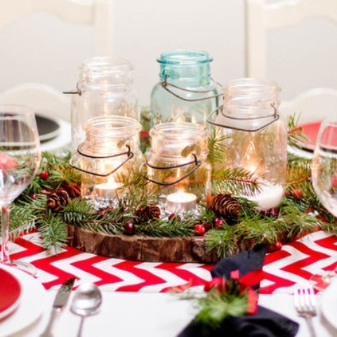 a rustic Christmas wedding centerpiece of a wood slice, ir, pinecones and jars with candles is very cute