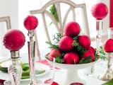 a bold Christmas wedding centerpiece of a stand with fir branches, red ornaments and tall stands with red ornaments