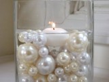 a refined Christmas wedding centerpiece of pearly and white Christmas ornaments and a floating candles