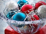 a colorful Christmas wedding centerpiece of a glass bowl with blue, red and silver Christmas ornaments is a cool idea to rock