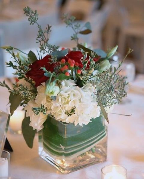 a chic and elegant Christmas wedding centerpiece of white, burgundy blooms and greenery is a stylish decoration