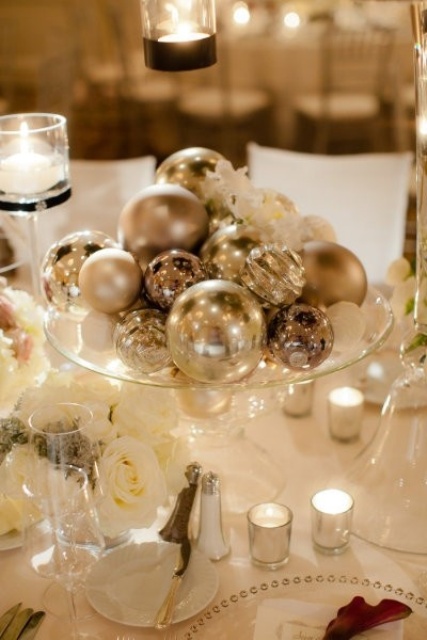 an easy and budget-friendly Christmas wedding centerpiece of a glass stand with various shiny ornaments can be DIYed