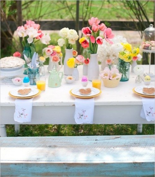 a bright and pastel wedding tablescape with white, pink, yellow blooms, blue vases, floral napkins is a fun and pretty idea for a spring wedding