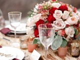 a refined fall wedding tablescape with pink and red roses, pale leaves, burgundy napkins, candleholders and gold cutlery is very chic