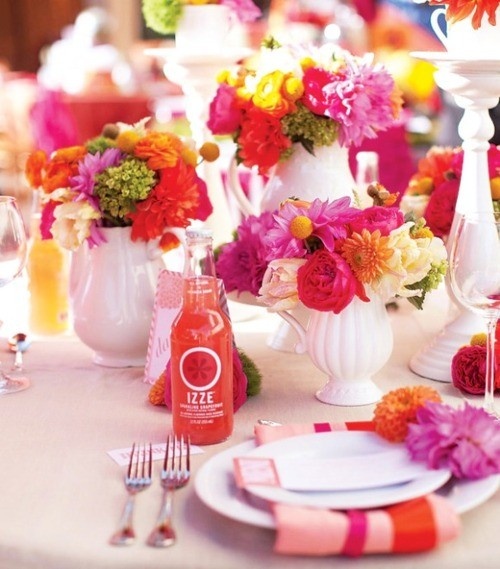 a bold summer wedding tablescape with red, hot pink, orange and yellow blooms, colorful napkins, bold drinks is a fun and cheerful idea