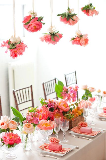 a bright wedding tablescape with pink, peachy and blush blooms and greenery, pink favors, pink blooms over the table is a beautiful idea for summer