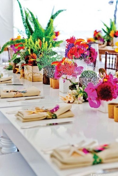 a colorful tropical wedding table setting with super bold blooms and greenery, corals, bold blooms accenting the napkins and succulents is wow