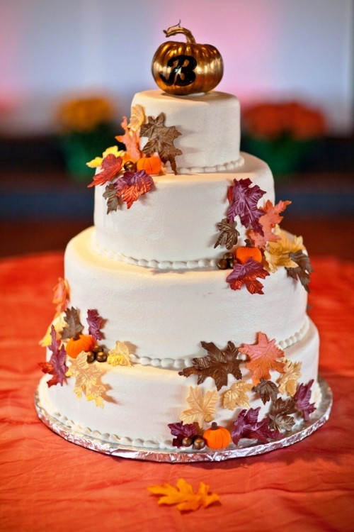 a fall wedding cake decorated with bright sugar leaves and pumpkins and a shiny pumpkin topper