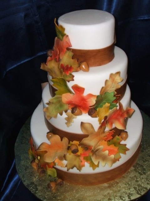 a fall wedding cake with brown ribbons, bright sugar leaves and acorns is a traditional way to embrace the season