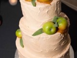 a textural buttercream wedding cake in blush, with pears and apples attached to the cake with caramel