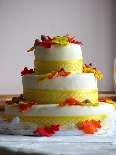 a bright fall wedding cake with neon yellow ribbon, sugar leaves and acorns for a bold look
