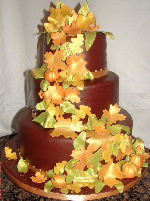 a chocolate wedding cake topped with bright sugar leaves and pumpkins is a statement idea