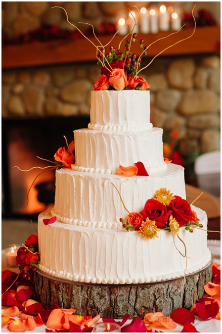 a textural white buttercream wedding cake with branches and bold fall blooms for decor